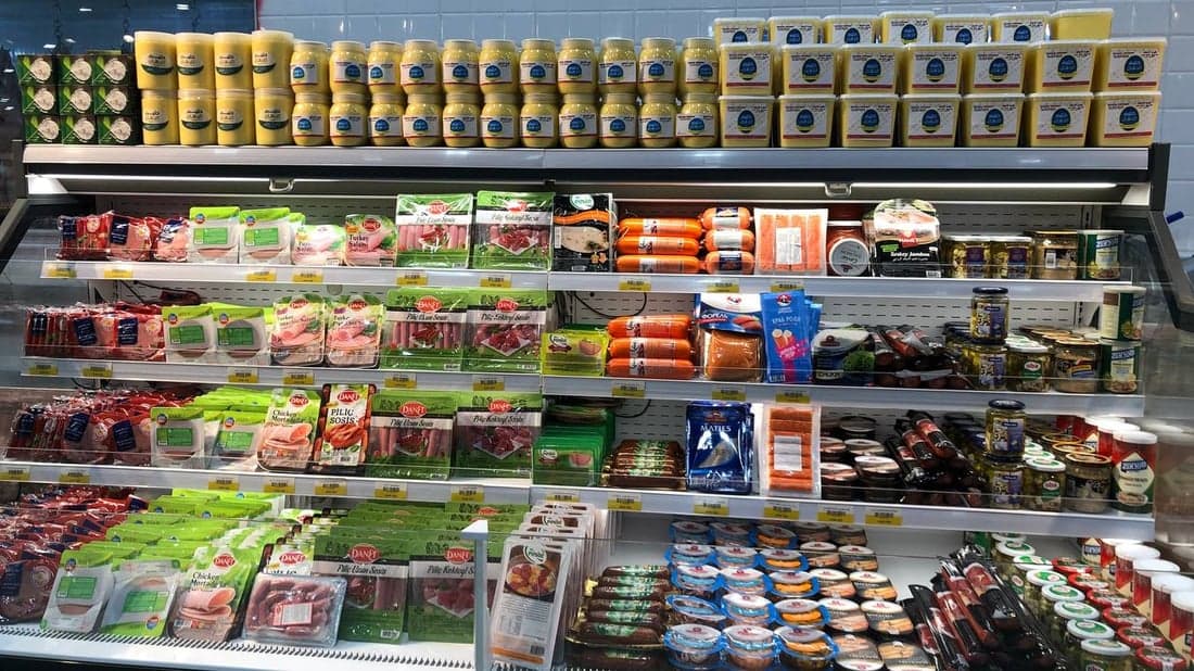 Refrigerated packaged-food shelf with an isolated empty facing in an Iraqi hypermarket
