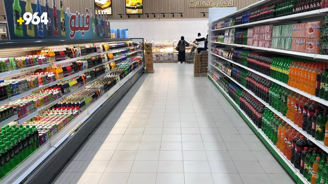 Multiple soft-drink brands displayed across an Iraqi supermarket aisle